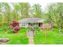 Charming brick home featuring a lush green lawn, mature trees, and a wooden bridge walkway at 8329 S Christian Dr, Nineveh, IN 46164