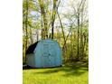 Outdoor shed with double doors amidst a lush green lawn and wooded backdrop at 9067 Old Haggard Rd, Morgantown, IN 46160