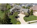 Aerial view showcasing the home's elegant exterior, manicured lawn, and inviting curved driveway to a two-car garage at 10138 Backstretch Row, Fishers, IN 46040