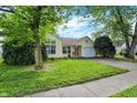 Beautiful yellow house with lush green lawn and mature trees shading the property at 1127 Jody Ct, Greenwood, IN 46143