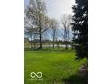 Expansive backyard with lush green grass and mature trees, offering privacy and scenic views of the water at 12353 Brean Way, Fishers, IN 46037