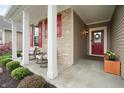 Inviting front porch featuring red door, rocking chairs, and beautiful landscaping at 16201 Haywood St, Fishers, IN 46037