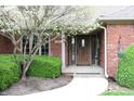 Inviting home entrance with charming brick facade, decorative tree, and covered front porch at 215 Fairway Ct, Franklin, IN 46131