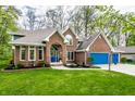 Charming brick home with manicured lawn and blue garage doors provides great curb appeal at 225 Yorkshire E Blvd, Indianapolis, IN 46229