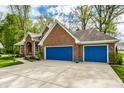 Attached two car garage doors colored a bright blue provides ample parking and storage at 225 Yorkshire E Blvd, Indianapolis, IN 46229