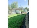 Expansive backyard featuring a well-maintained lawn, a detached garage, and a charming white picket fence at 25 N Wayburn St, Indianapolis, IN 46229