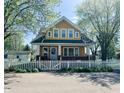 Charming two-story home with yellow siding, white trim, and a welcoming front porch and white picket fence at 25 N Wayburn St, Indianapolis, IN 46229