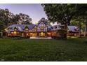 Tudor-style home with outdoor seating area, lush green lawn, and warm exterior lighting at 8103 N Pennsylvania St, Indianapolis, IN 46240