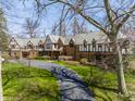 Stately Tudor-style home with a long driveway, manicured lawn, and mature trees at 8103 N Pennsylvania St, Indianapolis, IN 46240