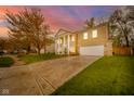 Classic brick home with a grand entrance, columns, and a beautiful landscaped front yard against a colorful sunset at 10090 Eagle Eye Way, Indianapolis, IN 46234