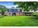 Classic two-story home with brick and blue siding, complemented by a lush green lawn and mature trees at 1095 Williamsburg Ln, Zionsville, IN 46077