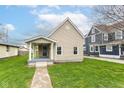 Charming tan single-story home featuring a welcoming front porch and well-manicured lawn at 1523 S K St, Elwood, IN 46036