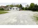 Charming single-story home with white siding, black shutters and a gravel driveway at 223 E 53Rd St, Anderson, IN 46013