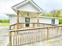Welcoming front porch with wooden railings and ramp provides accessible entry to the home at 223 E 53Rd St, Anderson, IN 46013