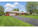 Traditional brick home with a long, paved driveway, attached garage, and manicured lawn in a residential area at 4044 Roamin Dr, Greenwood, IN 46142