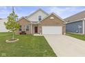 Charming brick home featuring an attached two-car garage and a well-manicured lawn at 5423 Maywood Dr, Whitestown, IN 46075