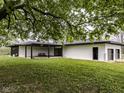 Spacious backyard featuring a covered patio, picnic table, lush green grass, and a full tree at 5707 S Burlington Dr, Muncie, IN 47302