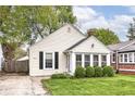 Quaint home with bright siding, black shutters, a brick chimney, green shrubs, and a lush lawn at 6167 Ralston Ave, Indianapolis, IN 46220