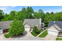 An expansive aerial view shows a charming single-story home nestled among lush trees and manicured lawns at 65 Palomino Ct, Zionsville, IN 46077