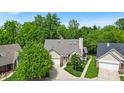 A serene aerial view captures a charming single-story home nestled among lush trees and manicured lawns at 65 Palomino Ct, Zionsville, IN 46077
