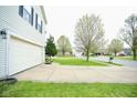 Wide driveway leading to a two-car garage, with a view of the tree-lined neighborhood at 6634 Frankenberger Dr, Indianapolis, IN 46237
