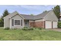 Inviting one-story home with a manicured lawn, brick accents, and an attached two-car garage at 7053 Colita More Nw Ct, Indianapolis, IN 46254
