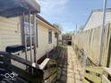 A view of the narrow side yard with a chain-link fence and a glimpse of the neighboring house at 907 W 14Th St, Muncie, IN 47302