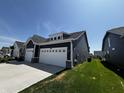 Side view of a navy blue house with a two-car garage, green grass, and blue sky at 1221 Malbec Cir, Westfield, IN 46074