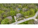 Aerial view of a home with a spacious driveway, lush landscaping, a neighboring house, and a tennis court in the background at 13 Ridgeline Dr, Brownsburg, IN 46112
