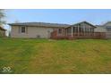 Large backyard featuring a wooden deck, sunroom, and well-maintained lawn at 1314 Brookside S Dr, Columbus, IN 47201