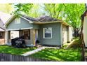 Quaint one-story home with green siding, inviting front porch, and lawn at 321 Harlan St, Indianapolis, IN 46201