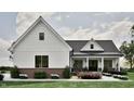 Inviting home with white siding, dark window trim, and a cozy covered porch surrounded by lush landscaping at 3932 Besbie Way, Bargersville, IN 46106