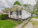 Charming home featuring white siding, a cozy front porch, and a beautifully landscaped front yard with green lawn at 411 Mccullen St, Chesterfield, IN 46017