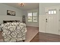 Cozy living room with a white front door, carpeted floors, wainscoting and a large window bringing in natural light at 4396 Nigella Dr, Plainfield, IN 46168
