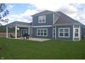 Back exterior featuring a covered patio with outdoor seating, a grill, and a spacious backyard at 4518 W Meadows Ln, New Palestine, IN 46163