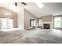 Spacious living room featuring vaulted ceilings, a fireplace, a skylight, and a neutral color scheme at 5204 Whipple Wood Ct, Indianapolis, IN 46226
