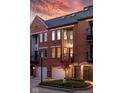 Brick townhome featuring well-maintained landscaping and private garage against a colorful sunset sky at 548 Lockerbie N Cir, Indianapolis, IN 46202