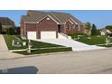 Attractive brick home featuring a manicured lawn, convenient two-car garage, and inviting front entrance at 5601 Harness Dr, Greenwood, IN 46143