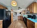 Cozy kitchen with wood cabinets, black appliances, and wood-look flooring at 741 Springmill Dr, Mooresville, IN 46158