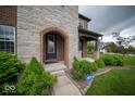 Close-up of the front entrance showcasing the stone archway and manicured bushes at 9949 Stable Stone Ter, Fishers, IN 46040