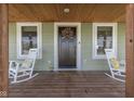 Welcoming front porch featuring rocking chairs, a dark wood door with wreath, and a 'welcome' mat at 10776 S 250 W, Flat Rock, IN 47234