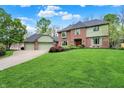 Charming brick home featuring a well-kept lawn, mature trees, and a three-car garage at 13494 Dallas Ln, Carmel, IN 46033