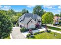 Aerial view of a stunning brick home with a three car garage, lush greenery, and a circular driveway at 13934 Salsbury Creek Dr, Carmel, IN 46032