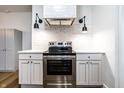 Updated kitchen features modern stainless steel stove, range hood, white cabinets, and subway tile backsplash at 1451 N Grant Ave, Indianapolis, IN 46201