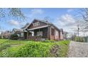 Side view of a craftsman-style home with mature landscaping and a detached garage at 21 N Bosart Ave, Indianapolis, IN 46201