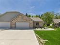 Brick home with a three car garage, concrete driveway, and covered walkway on a lush lawn at 2327 Mimosa Ln, Anderson, IN 46011