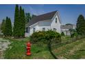 A quaint white home with dark roof, green lawn, and tidy landscaping at 2402 N B St, Elwood, IN 46036