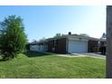 Brick home with an attached garage surrounded by a green lawn at 2630 Wedgewood Dr, Columbus, IN 47203