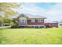 View of the back of this home with a large manicured lawn and wooden stairs leading to the back door at 300 E 2Nd St, Sheridan, IN 46069
