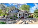 Charming single-story brick home with lush landscaping and stone accents at 6149 W Olive Branch Rd, Greenwood, IN 46143
